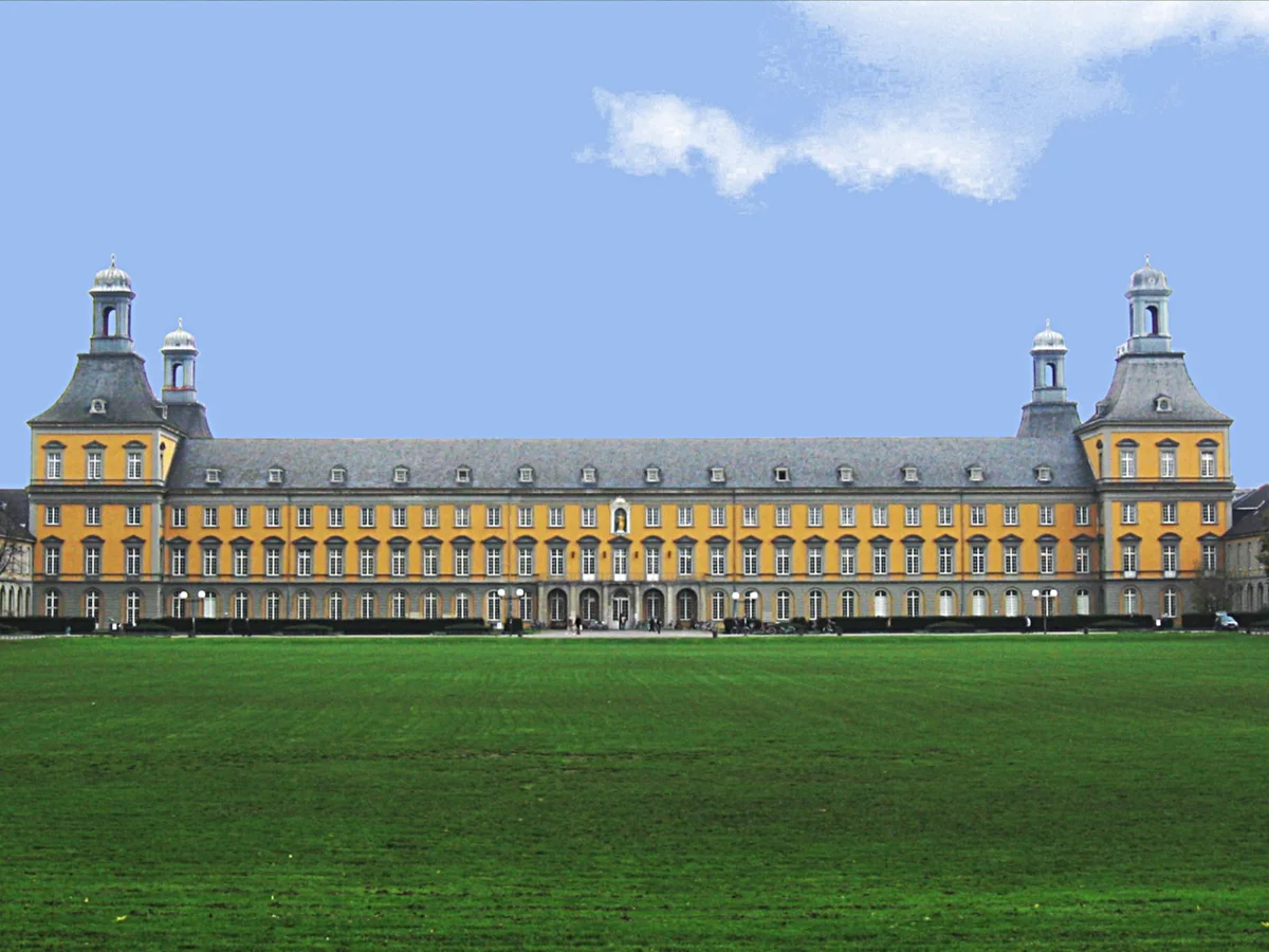 Bonn Üniversitesi ana binasının Hofgarten çim alanından görünen sarı cephesi